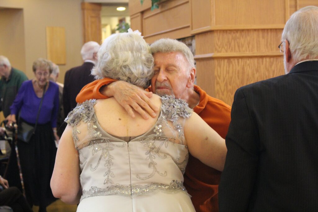 senior living residents embrace in hug