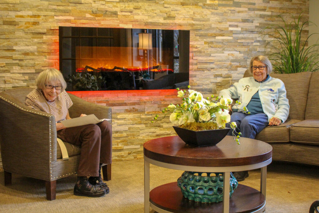 female senior living residents by fireplace