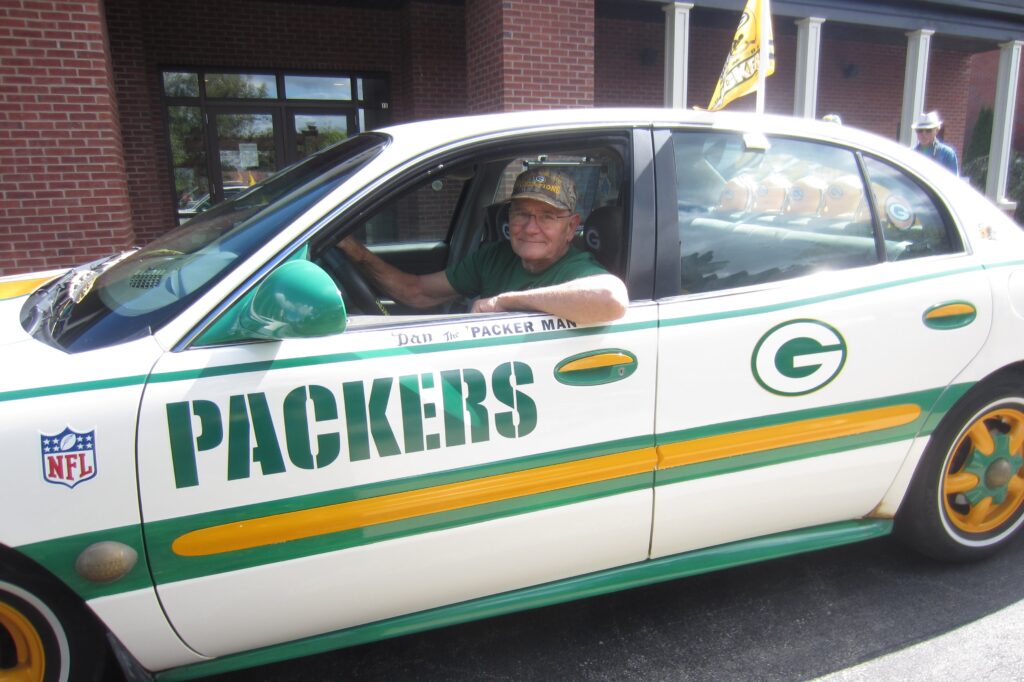 older adult driving car with Green Bay Packers decorations