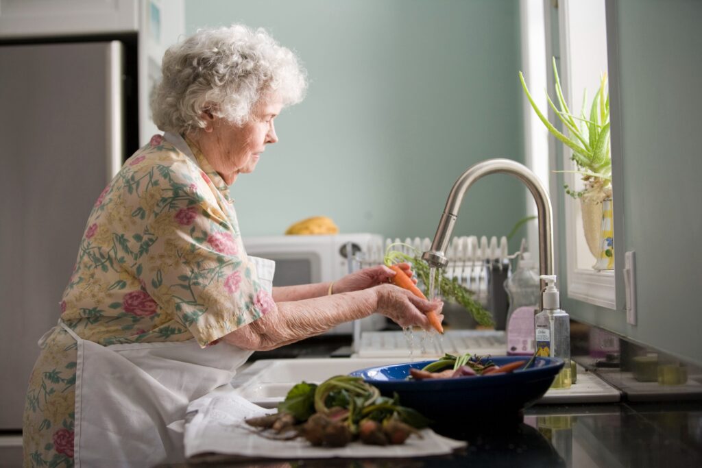 Elderly woman cleaning vegetables for cooking