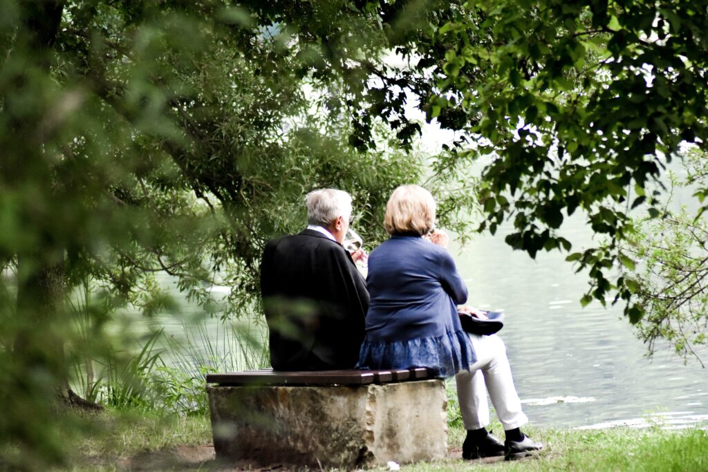 older couple sitting at the edge of a lake