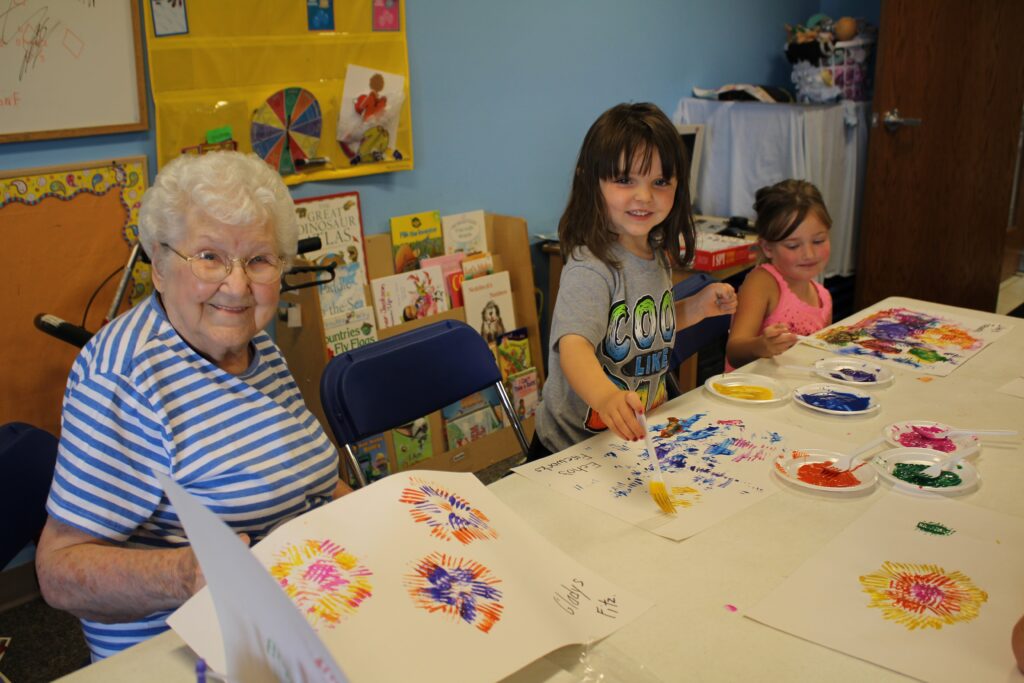 older woman painting with young children